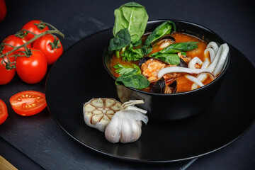 Soup with seafood and vegetables. Still life on a dark background.