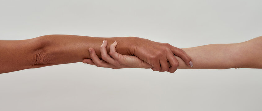 Close Up Shot Of Two Female Hands Rescuing Or Holding Each Other Strongly Isolated Over Light Background