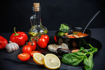 Soup with seafood and vegetables. Still life on a dark background. Shrimps and squid in fish broth.