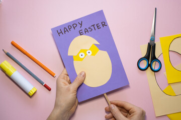 Fototapeta premium Easter greeting card in egg shape. How to make children's paper craft. Step 11. Simple creative art project. Step by step instructions. Homemade easy paper applications. DIY concept.