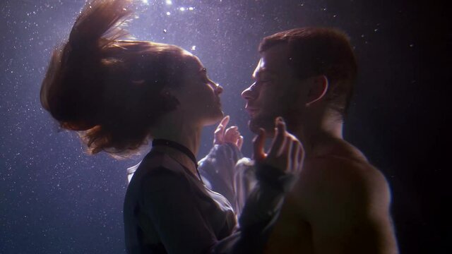 two lovers underwater, man and woman are embracing in deepness, romantic subaquatic shot