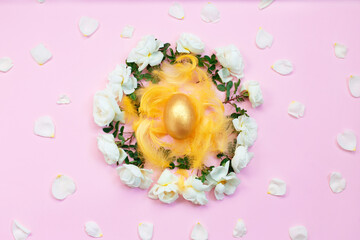 Gold Easter egg on nest from white roses and petals.