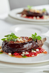 Half baked eggplants with meat, cheese and tomatoes on white background. Banquet festive dishes. Gourmet restaurant menu. White background.