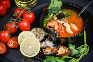 Soup with seafood and vegetables. Still life on a dark background.