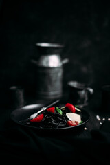 Black pasta with tomatoes and parmesan in a black plate