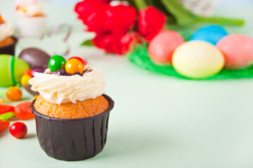 Easter cupcake with candy eggs, colorful eggs on a festive table. Copy space.