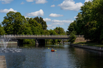 Unrecognizable people doing standup paddle and riding kayaks at river and bridge view on a sunny day in Perth, Ontario, Canada