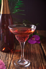 Summer tropical pink cocktail wine champagne decorated purple orchid flowers on the wooden table.