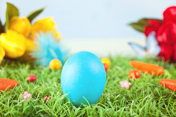Fototapeta na wymiar Blue color easter egg in the grass with flowers tulips on the background
