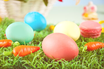 Fototapeta na wymiar Colorful Easter eggs in the grass with carrots candy