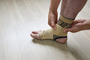 Human hands fix an elastic bandage sock to protect the ankle of the leg from sprains
