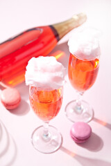 Glasses with sweet cotton candy pink cocktail and bottle on background