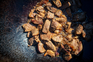 The meat is fried in a cauldron.