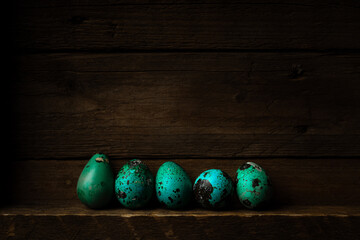 Small speckled Easter eggs colored blue on dark wooden rustic background