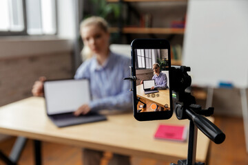  Happy young smart businesswoman filming educational tutorial or sharing professional skills. Focus on phone screen