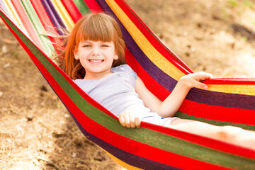 Fototapeta na wymiar Summer vacation. Lovely child girl rest in colorful hammock outdoor in summer forest
