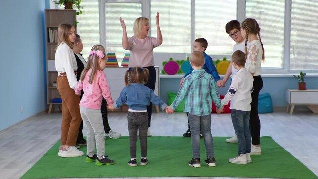 friendship between healthy children and people with down syndrome, kids and female teacher stand together in circle holding hands