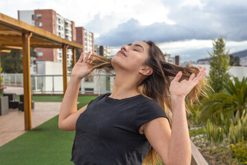 Portrait of a teenage girl breathing and combing her hair outdoors