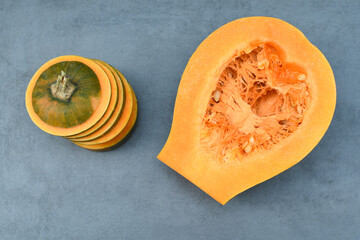 Sliced ​​pumpkin with seeds, close-up on a gray background. Orange ripe pumpkin. Healthy eating. Copy space