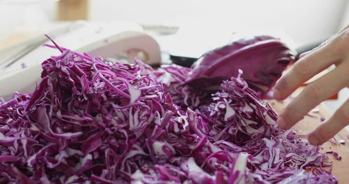 Red cabbage cut into thin slices using kitchen mandoline slicer, sauerkraut making process, close up
