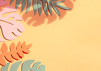 Hand cut paper tropical plants leaves on the orange background. Summer concept Top view. Copy space