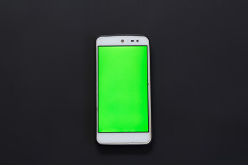 Smartphone with green screen on black background.