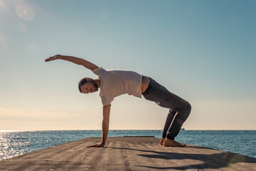 Attractive young man practicing yoga meditation and breathwork outdoors by the sea