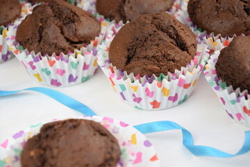 Chocolate cupcakes with alamonds, colorfull hearts on liners, blue ribbon, valentine cake