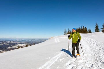 Fototapeta na wymiar Man snowshoeing in the Alps under a clear blue sky.
