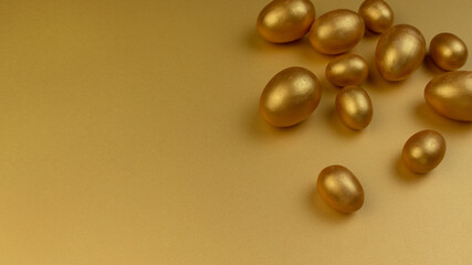 Decorative wooden Easter eggs painted gold on yellow-gold background. Happy Easter greeting card.