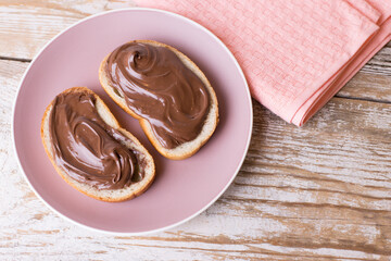 Spread the chocolate-nut cream on slices of bread. Delicious Breakfast with chocolate and nut paste. Copy space.