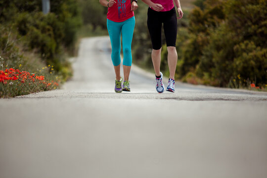 Detail photo of two woman running on a street in the landscape focus on their feet