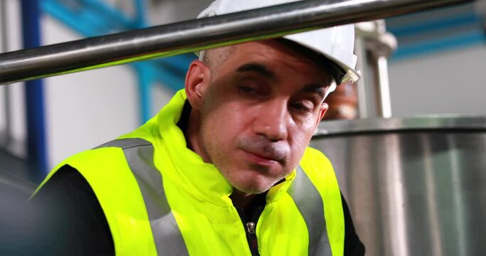Stressed exhausted factory engineer man in drinks production plant. Food and beverage industry factory concept.