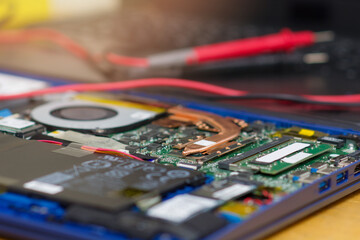 macro shot of an electronic microcircuit and a multimeter lying on a laptop. The concept of equipment repair and soldering of microcircuits online on the Internet.