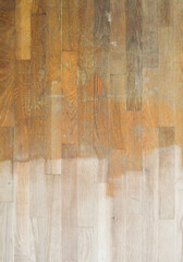 Wood floor that is being refinished, sanded floor on bottom and original floor on top