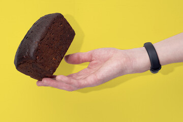 Loaf of rye bread, balanced on a hand with fitness band. Concept of sustainable consumption and healthy nutririon.