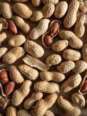 Peanuts in shells and peeled scattered on brown craft paper in the morning light