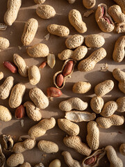 Peanuts in shells and peeled scattered on brown craft paper in the morning light