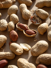 Peanuts in shells and peeled scattered on brown craft paper in the morning light