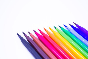 Multi-colored markers with a brush tip, arranged according to the colors of the rainbow. White background. The concept of creativity, drawing, bright world, back to school, study. Copy space