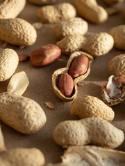 Peanuts in shells and peeled scattered on brown craft paper in the morning light