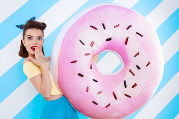 Wow pop art face. Sexy surprised woman with donuts in hands and open mouth. Colorful background in pop art retro comic style on striped blue background. Pinup and pop art concept