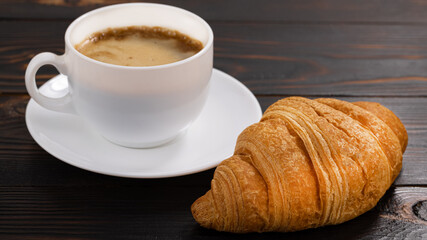 cup of coffee and croissant on wooden table. Top view