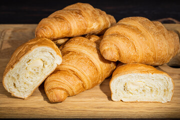 fresh croissants on wooden board on a dark background