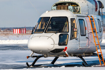Fototapeta na wymiar Close-up of a white helicopter with an open engine on the apron of a winter airport