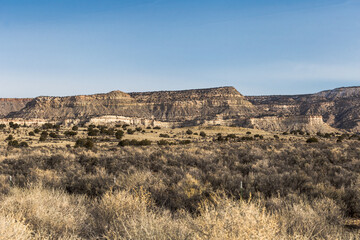 Open desert fields with brush and rocky mountains on clear day in rural New Mexico