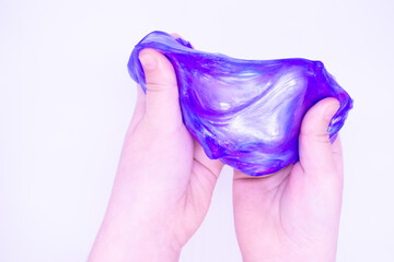 Fototapeta premium Close up of game with two-color blue and pink slime in someones hands on a white background. The mucus is crushed, stretched, torn and squeezed by hands