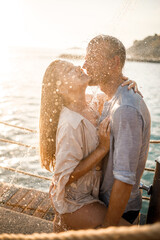 Fototapeta premium Beautiful couple in love hugs and kisses under the streams of water in a luxury spa hotel on their honeymoon, vacation in the tropics. Selective focus