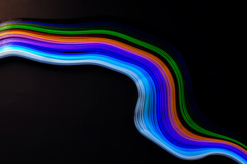 Abstract color wave curl rainbow strip paper on black background