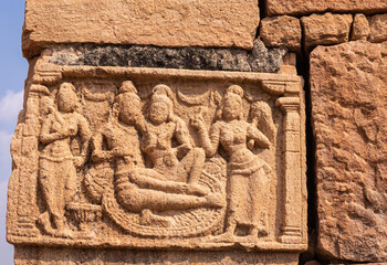 Bagalakote, Karnataka, India - November 7, 2013: Pattadakal temple complex. closeup of damaged brown stone sculpture of Vishnu reclining on Sesha-Naga snake in company of his wives.